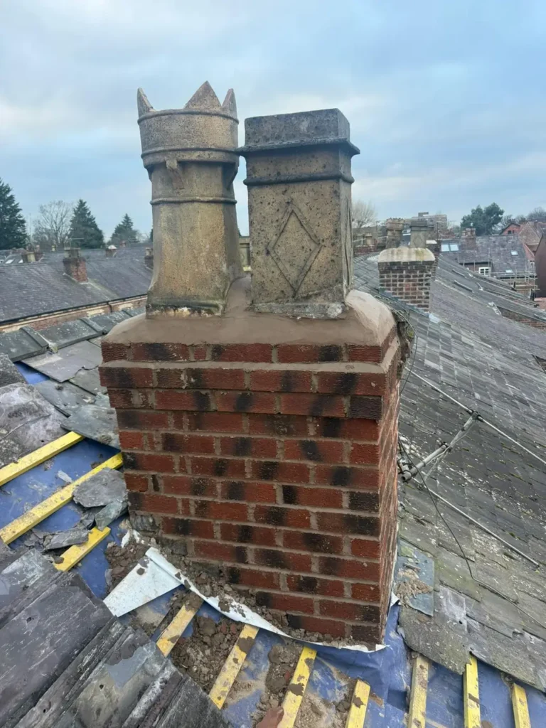Chimney stacks with pots before repair on an old slate roof