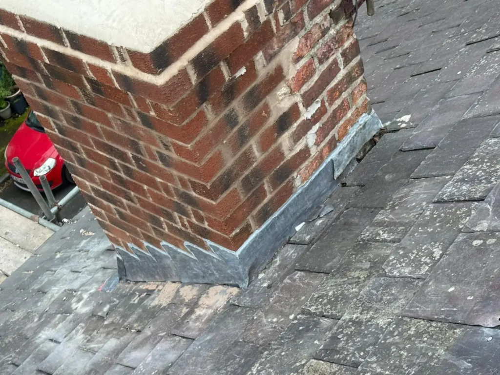 Lead flashing at the base of a brick chimney