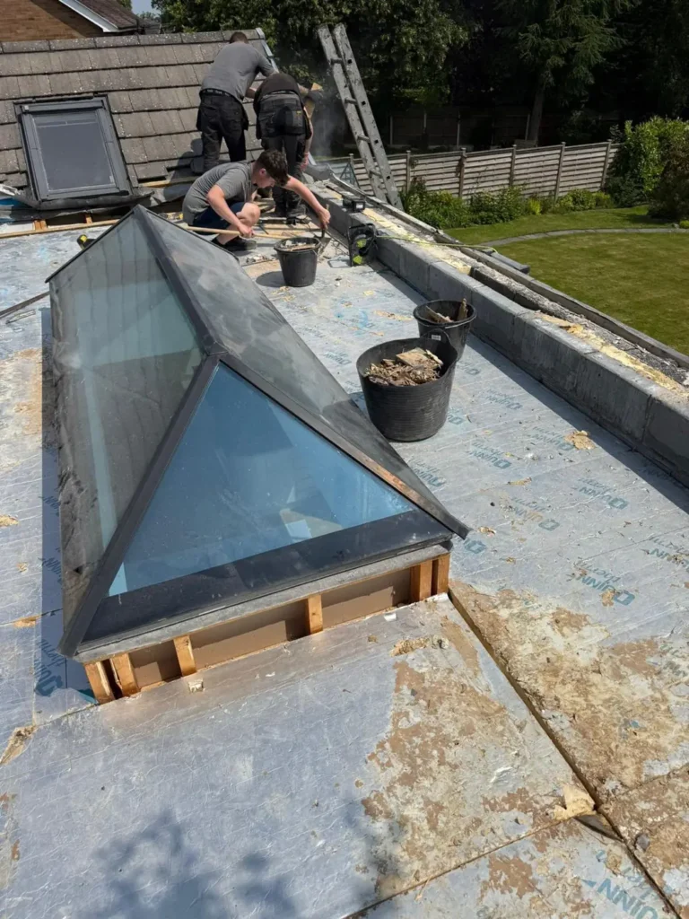 Roofers fitting a glass rooflight on a flat roof