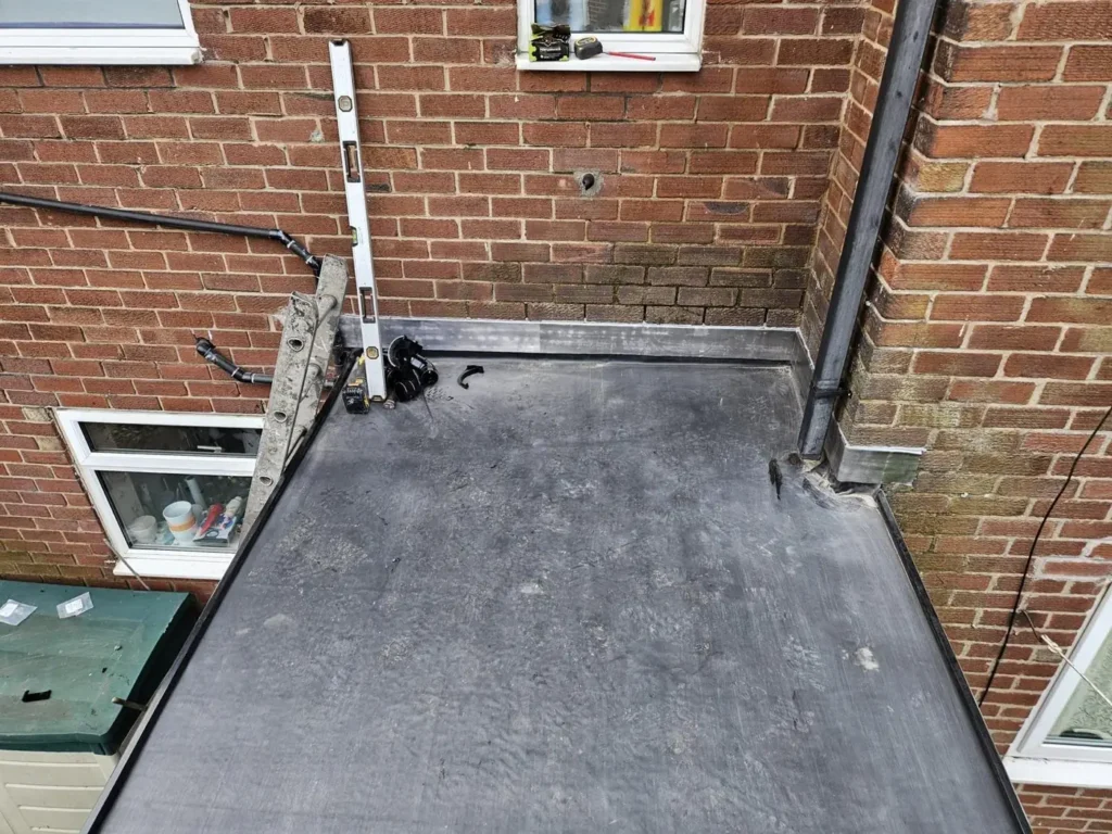 Flat roof with upstand against a brick wall