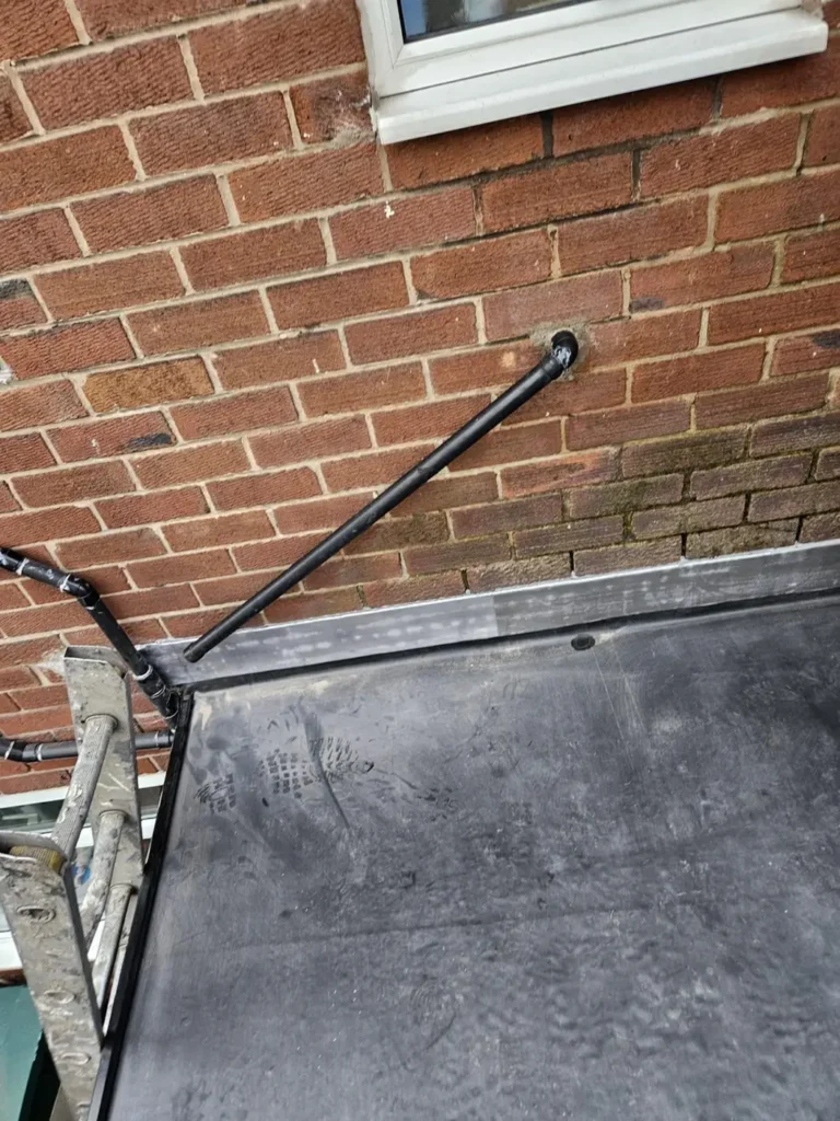Flat roof edge and upstand against a brick wall